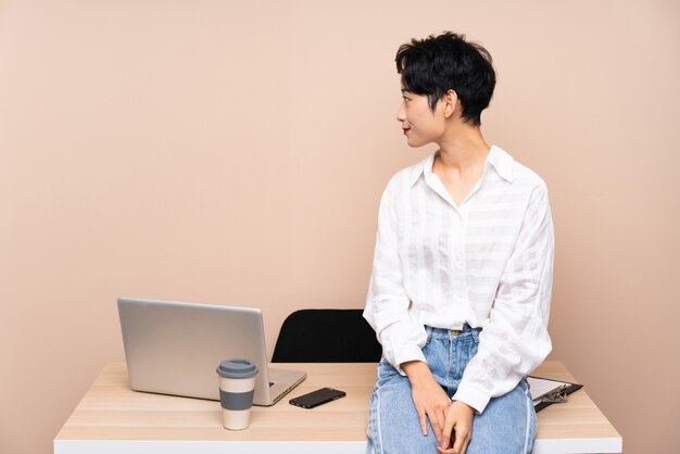 Ragazza asiatica di giovani affari nel suo posto di lavoro che guarda al lato