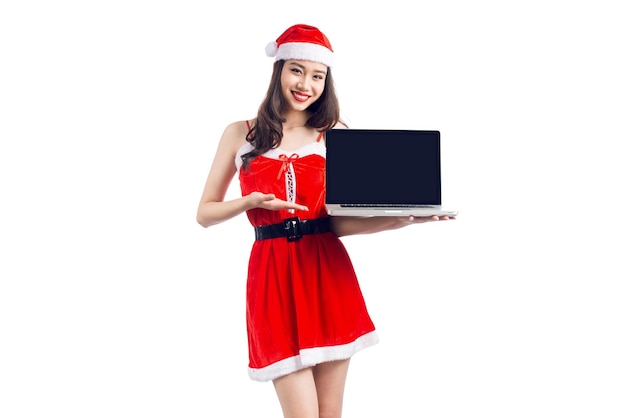 Ragazza asiatica di Natale con i vestiti di Babbo Natale che tengono il computer portatile isolato su priorità bassa bianca