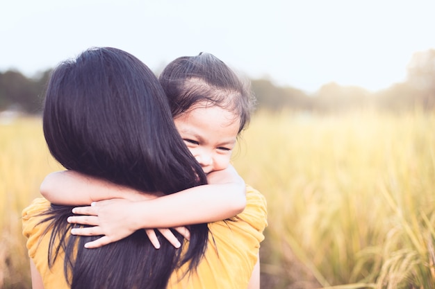 ragazza asiatica felice del piccolo bambino che abbraccia sua madre con amore nella risaia nel tono d&#39;annata di colore