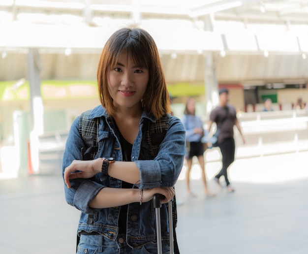 Ragazza asiatica felice del viaggiatore con bagaglio in grande città