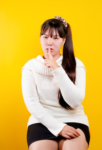 Ragazza asiatica Quel sorriso allegro, divertente e luminoso. espressione di occhi amorevoli, buon vivere e felicità sul lavoro, relax, su uno sfondo giallo