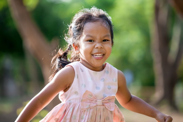 Ragazza asiatica sveglia del bambino che funziona nel parco