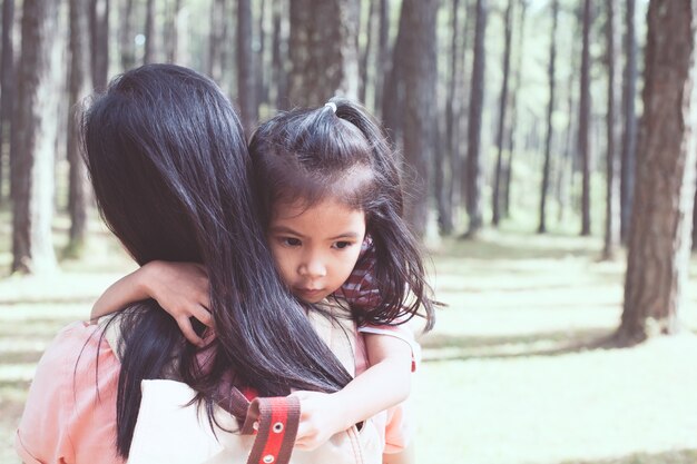 Ragazza asiatica sveglia del piccolo bambino che abbraccia sua madre