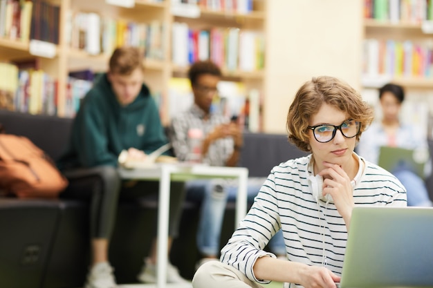 Ragazza astuta dello studente che lavora al progetto in biblioteca