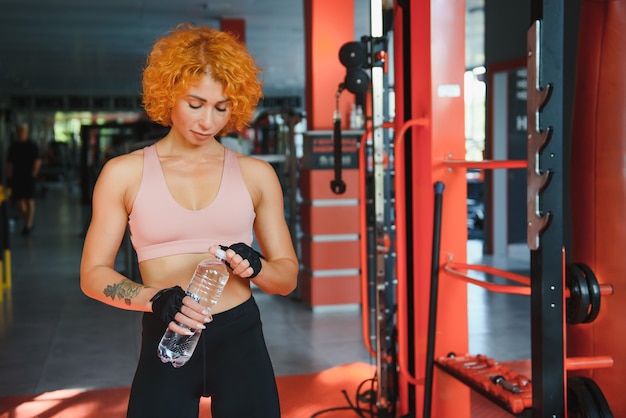 Ragazza atletica con acqua nelle sue mani in palestra