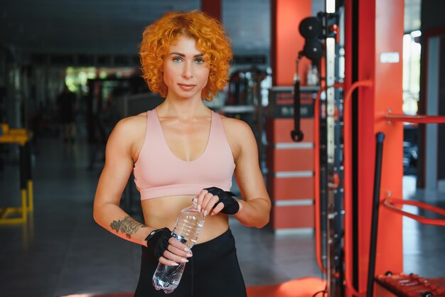 Ragazza atletica con acqua nelle sue mani in palestra