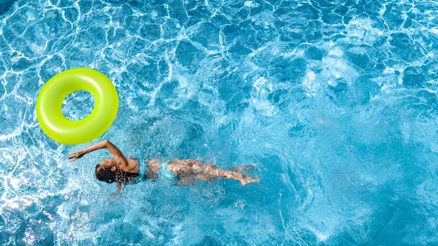 Ragazza attiva nella vista dall'alto aerea della piscina dall'alto il bambino nuota sull'anello gonfiabile