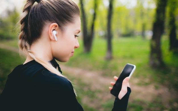 Ragazza attraente che utilizza il suo telefono mentre correndo nel parco