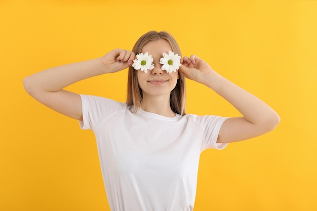 Ragazza attraente con fiori su sfondo giallo