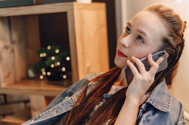 Ragazza attraente con il telefono che parla con qualcuno. Comunicazione tramite rete mobile.