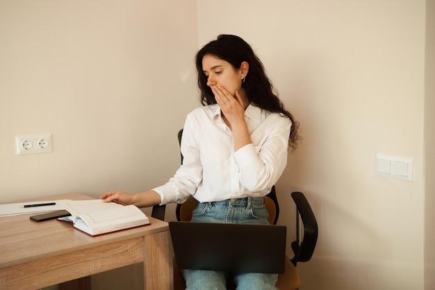 Ragazza attraente con laptop e documenti che lavorano online e scrivere note su carta e parlare per telefono Donna d'affari sicura di sé lavora a casa