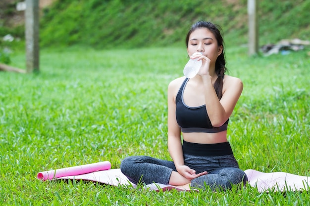 Ragazza attraente fitness sano con acqua potabile dopo l&#39;allenamento yoga