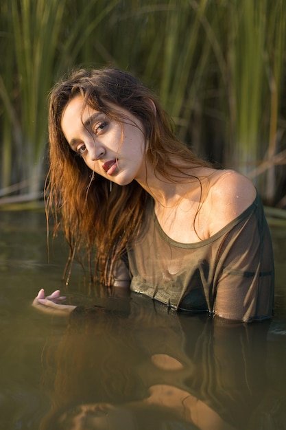 Ragazza bagnata in acqua con canne ritratto emotivo di una ragazza in acqua
