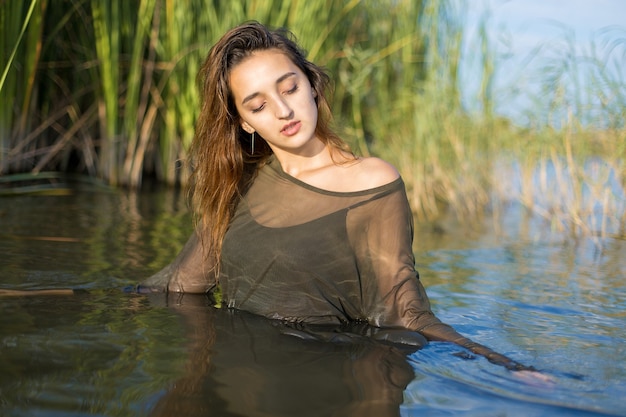 Ragazza bagnata nell'acqua con canne, ritratto emotivo di una ragazza nell'acqua