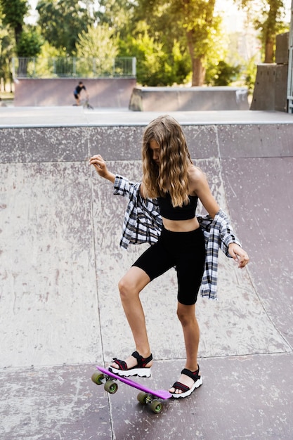 Ragazza bambino giro su penny board o skate board Attrezzature sportive per bambini Adolescente con penny board su skate park parco giochi