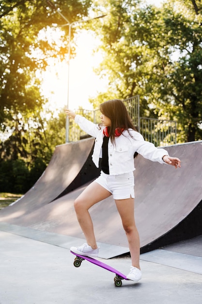 Ragazza bambino giro su penny board su skate rampa sportiva al tramonto Attrezzature sportive per bambini Adolescente attivo con pennyboard su skate park parco giochi