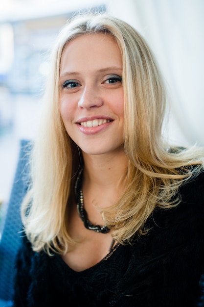 Ragazza bellissima giovane donna con un sorriso perfetto, seduto al caffè all'aperto