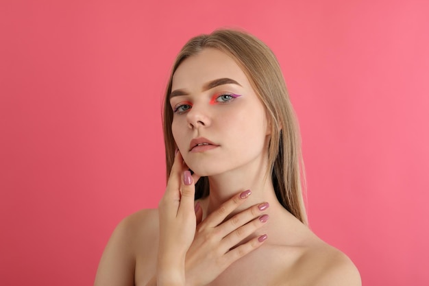 Ragazza bellissima modella con il trucco su sfondo rosa