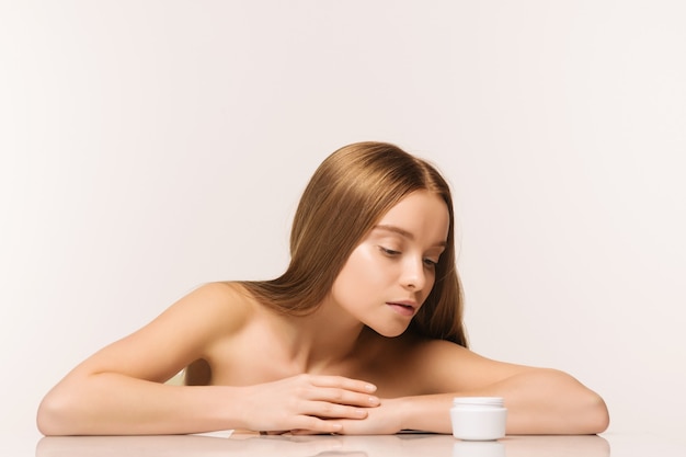 Ragazza bellissima spa con vasetto di crema isolato su sfondo bianco - immagine