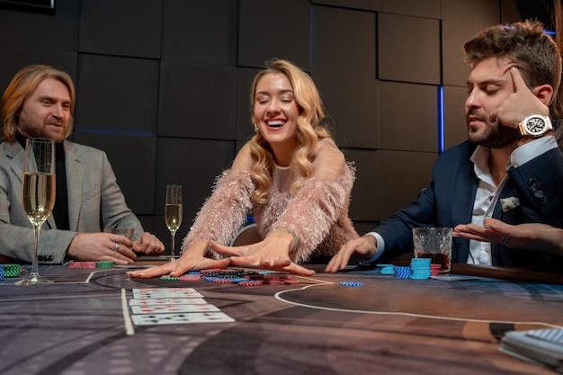 Ragazza bionda allegra che vince il gioco del poker e prende il piatto al tavolo da gioco