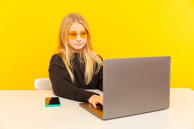 Ragazza bionda carina a casa davanti al computer portatile che fa video per vlog e lavora come blogger