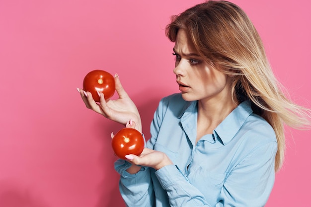 Ragazza bionda carina con pomodori in mano cibo sano sfondo rosa