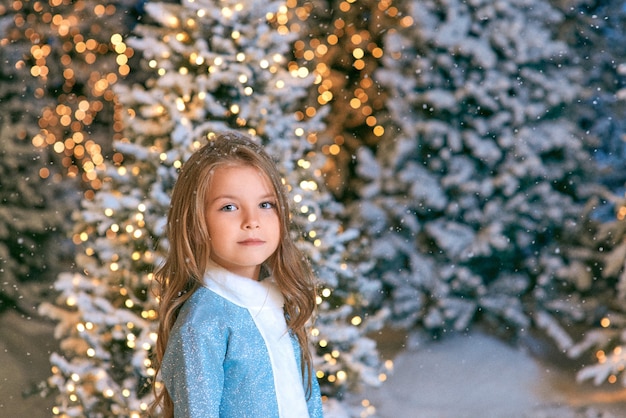 ragazza bionda caucasica che cammina nella foresta di natale invernale con luci