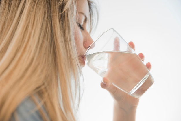 Ragazza bionda che beve bicchiere d&#39;acqua