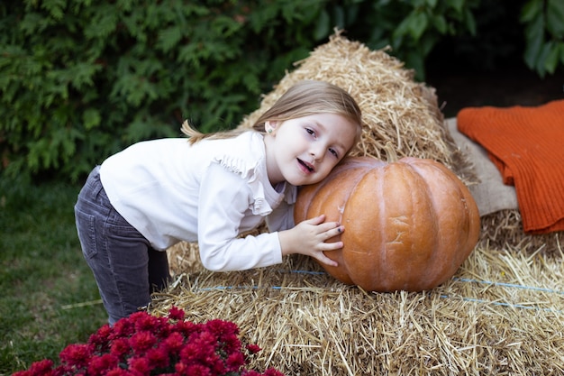 Ragazza bionda che gioca con la zucca in giardino