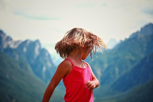 Ragazza bionda che lancia i capelli contro le montagne