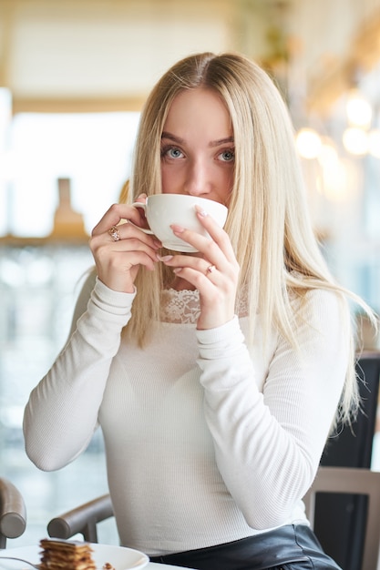 Ragazza bionda che mangia dolce in caffè