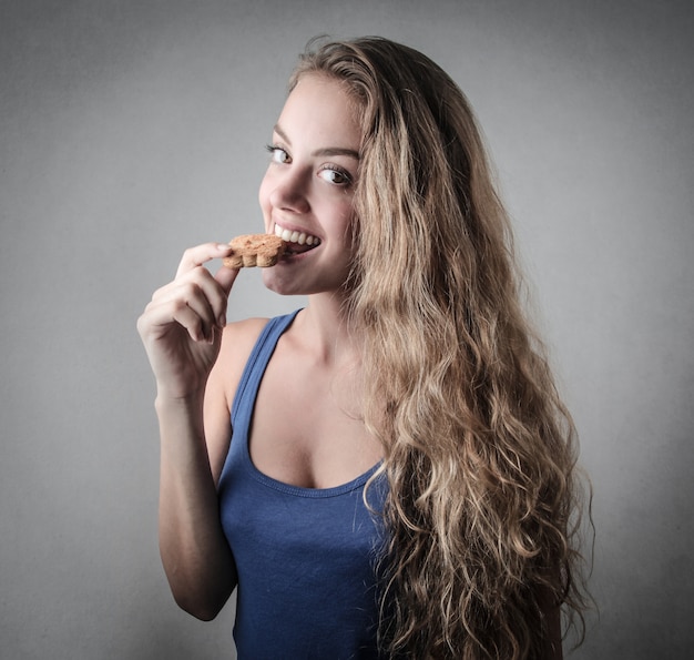 Ragazza bionda che mangia un biscotto