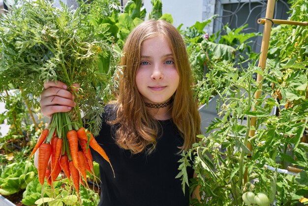 Ragazza bionda che raccoglie il frutteto urbano delle carote