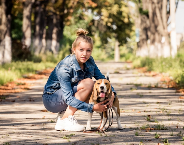 ragazza bionda che si siede con il cucciolo in un parco