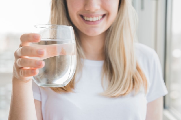 Ragazza bionda che tiene bicchiere d&#39;acqua