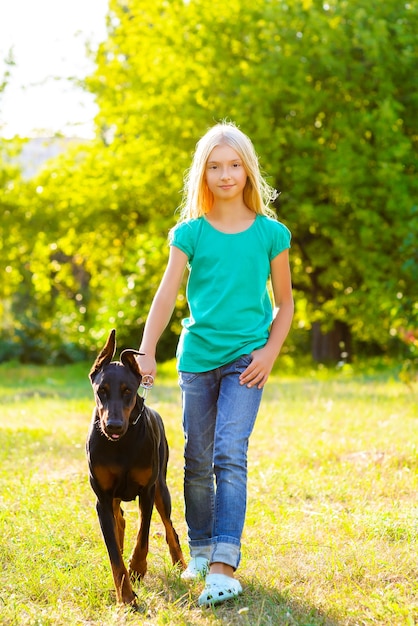 Ragazza bionda con doberman nel parco estivo