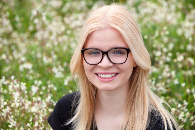 Ragazza bionda con gli occhiali circondato da fiori