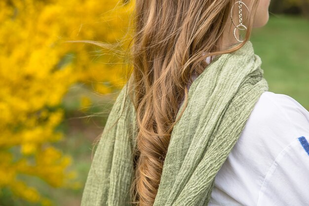 Ragazza bionda con una sciarpa elegante palude verde tra i fiori gialli luminosi