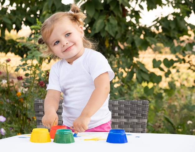 Ragazza bionda del bambino che dipinge con le dita