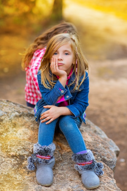 ragazza bionda del bambino pensierosa annoiata nella foresta all&#39;aperto