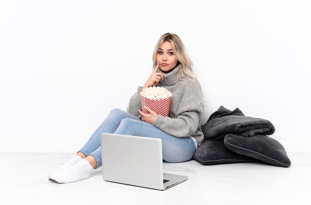 Ragazza bionda dell'adolescente che mangia popcorn mentre guarda un film