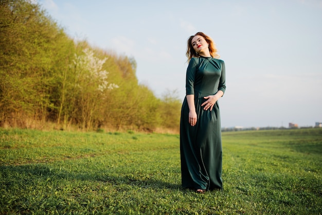 Ragazza bionda elegante di Yong al vestito verde sul giardino in primavera.