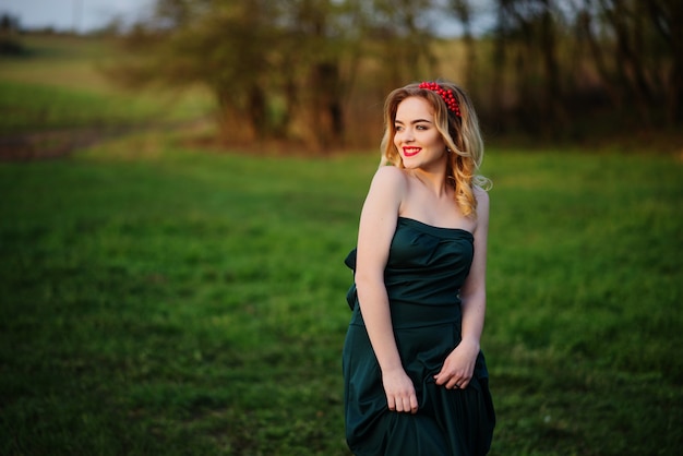 Ragazza bionda elegante di Yong al vestito verde sul giardino in primavera.