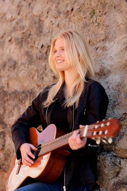 Ragazza bionda fresca che gioca chitarra all&#39;aperto