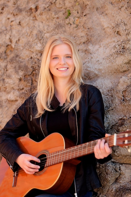 Ragazza bionda fresca che gioca chitarra all&#39;aperto