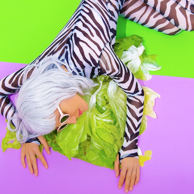 Ragazza bionda in abiti alla moda con stampa zebrata con sfondo verde insalata fresca Vai vegano amante degli animali Dieta cibo sano calorie concept Festa vegana crudaxA