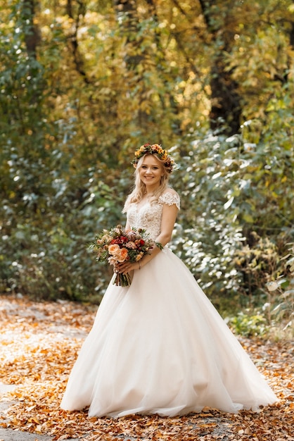 Ragazza bionda in abito da sposa nella foresta autunnale