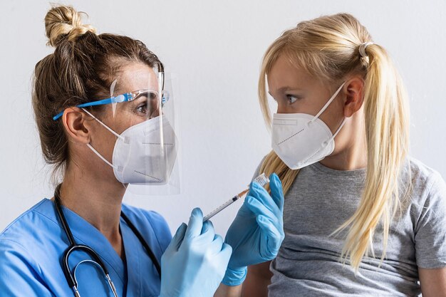 Ragazza bionda in maschera al centro di vaccinazione si vaccina Siringa con vaccino per covid19 influenza coronavirus malattie infettive pericolose Iniezione dopo studi clinici per bambino umano