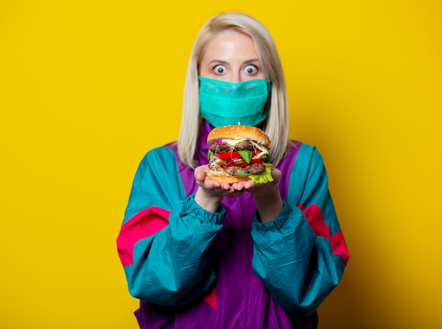 Ragazza bionda in maschera con hamburger