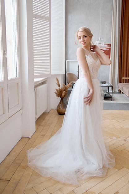 Ragazza bionda in un bellissimo abito da sposa bianco. Una sposa donna sta aspettando lo sposo prima del matrimonio